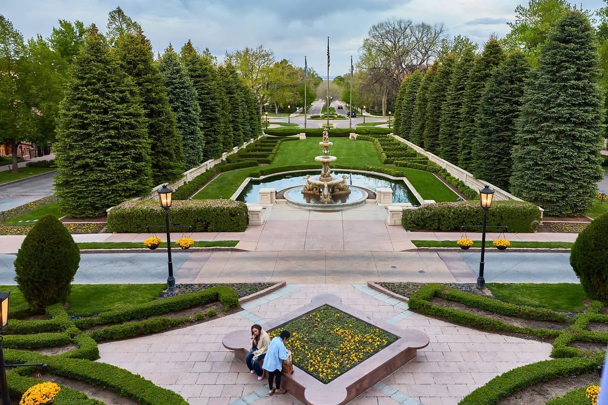 Two attendees talking on a bench above The Broadmoor's formal garden and fountain