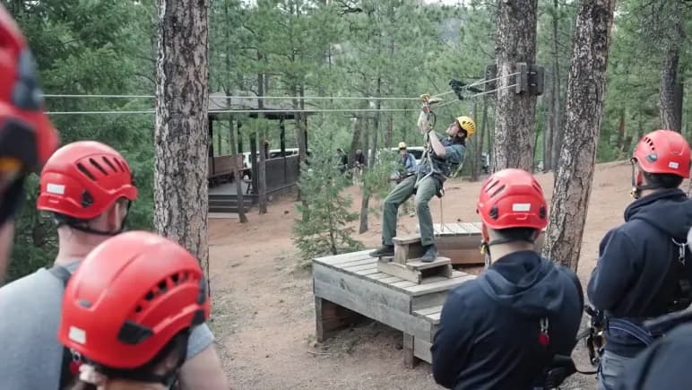 Attendees in helmets on the zipline platform above Seven Falls