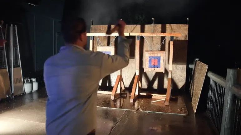 An attendee throwing an axe at a lit target