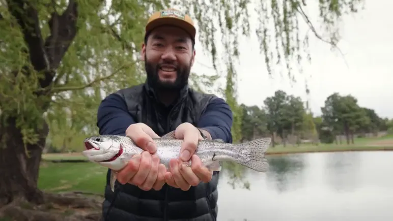 A guide holding a trout beside the pond