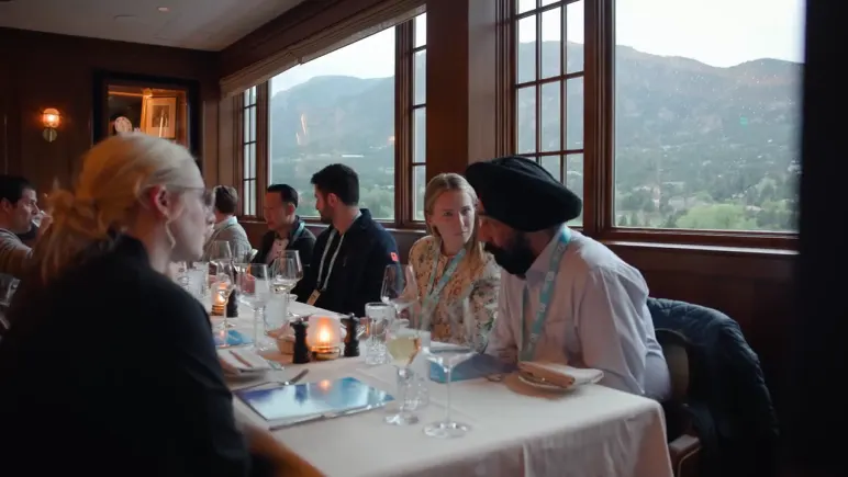 Practitioners at a long dinner table looking out at the mountains