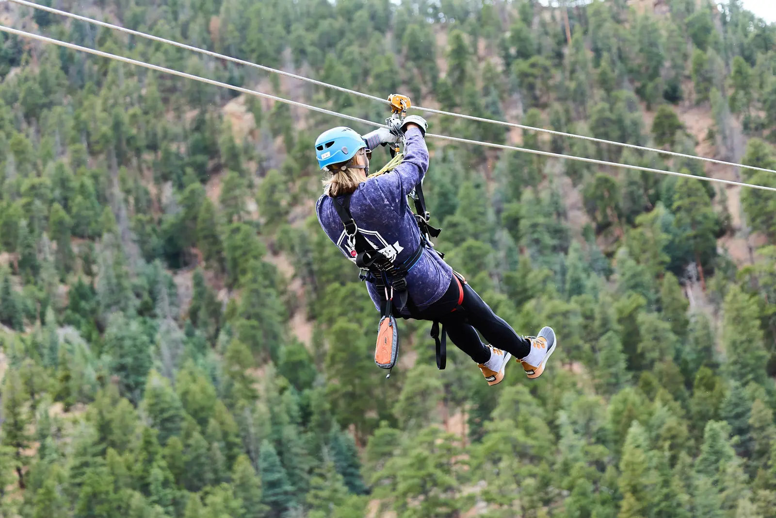 An attendee riding the zipline above the pines at The Broadmoor